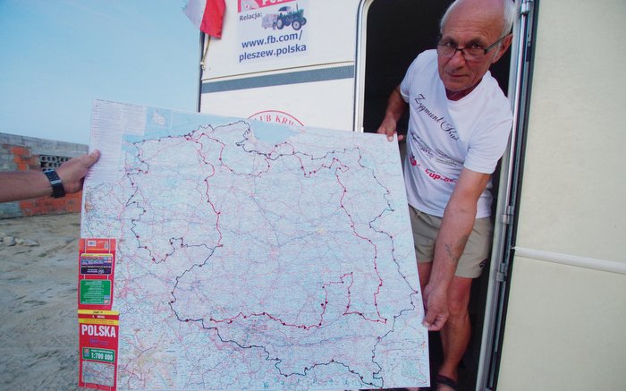 Zygmunt Kuś prezentuje mapę Polski, na której oznaczył punkty i trasę, jaką przez trzy lata przemierzył swoim niecodziennym zestawem karawaningowym