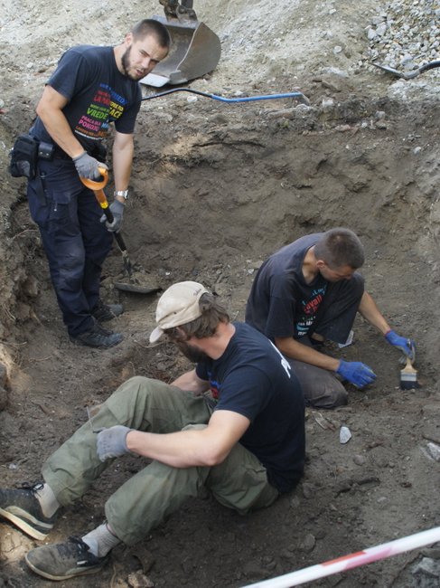 Pracami ekshumacyjnymi kierował Adam Białas (trzymający szpadel). Na górze odznaka znaleziona w grobie