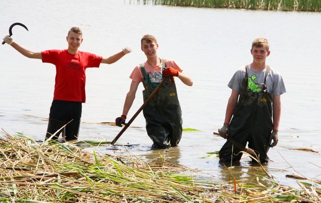 Młodzi wędkarze przygotowują stanowisko do łowienia ryb, brodząc w wodzie