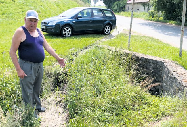 Jan Bojczuk, wieloletni sołtys Dankowic pokazuje fragment rowu przy drodze powiatowej, którego niecka jest wypełniona ziemią i prawie zrównana z wysokością jezdni 