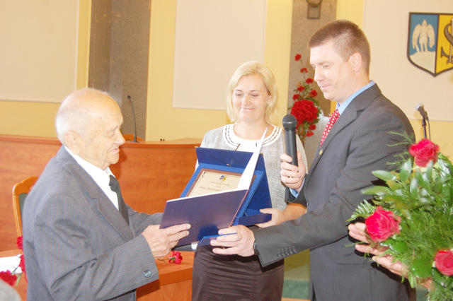 Burmistrz Dorota Pawnuk i przewodniczący RM Ireneusz Szałajko wręczają Marianowi Pindlowi akt nadania tytułu „Honorowy Obywatel Miasta Strzelina”